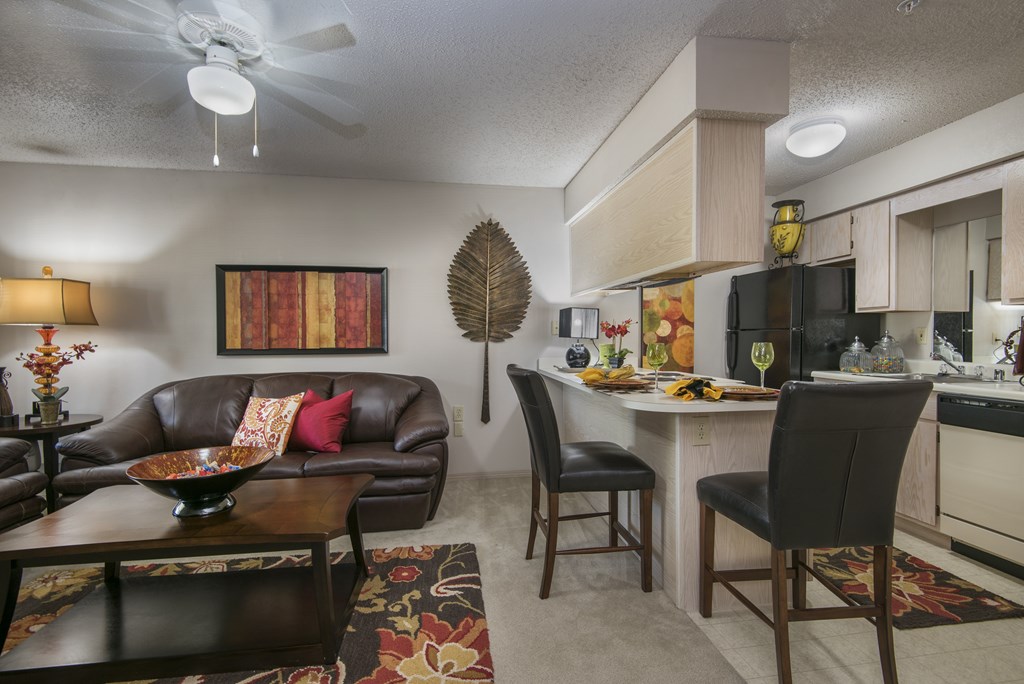 A living room with a brown couch and a dining table with chairs.