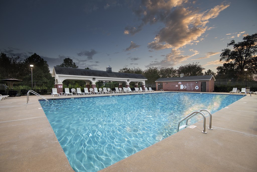 a swimming pool with chairs and a building in the background