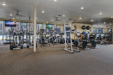 A gym with a variety of equipment including treadmills, weights, and exercise machines.