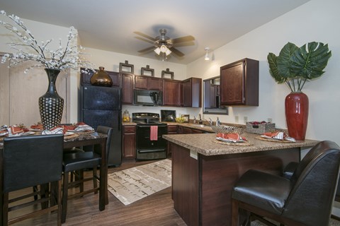 A kitchen with brown cabinets and a black counter.