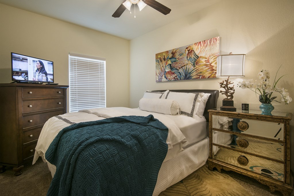 A bedroom with a bed, dresser, and ceiling fan.