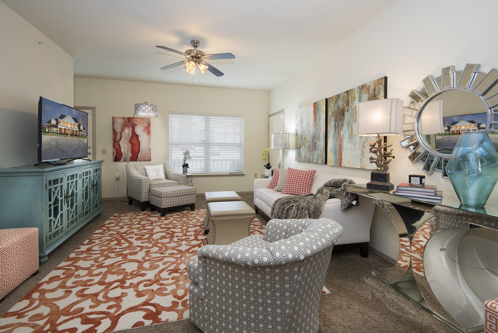 A living room with a patterned carpet and a ceiling fan.