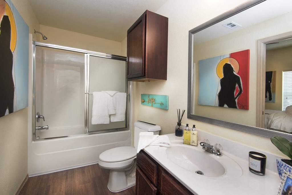 A bathroom with a toilet, sink, and mirror.