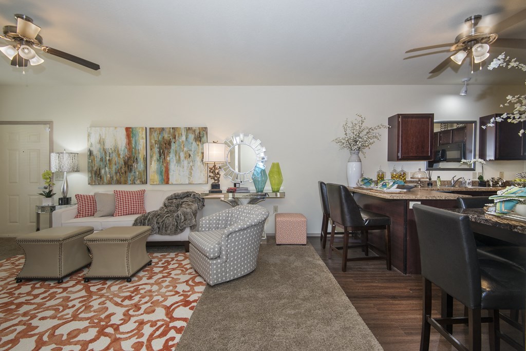 A living room with a patterned carpet and a kitchen area in the background.