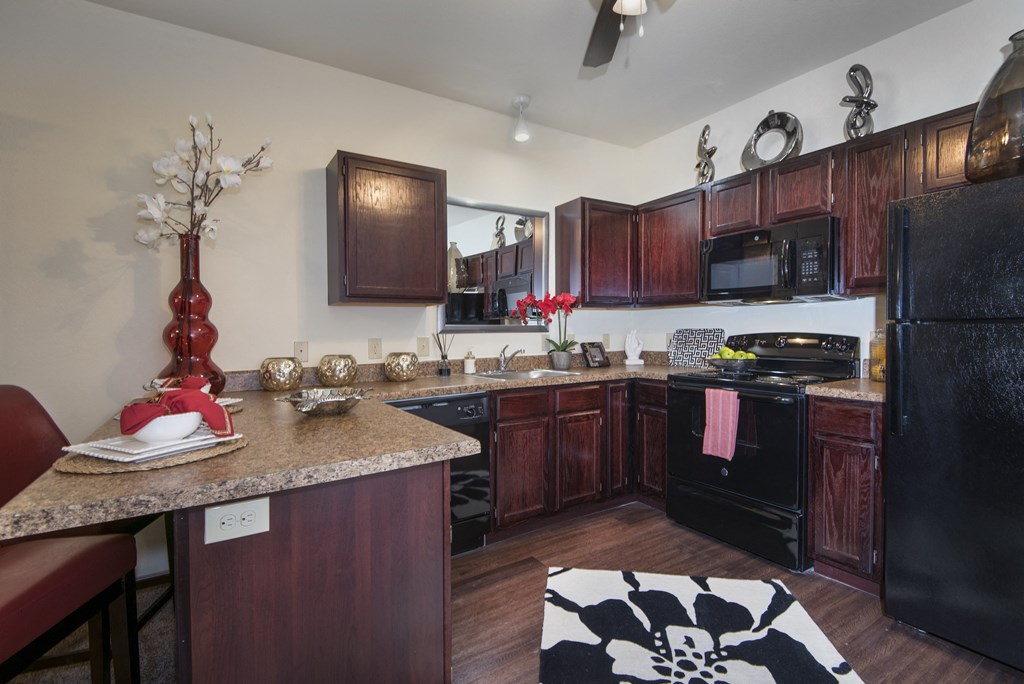 A kitchen with dark wood cabinets and a black refrigerator.