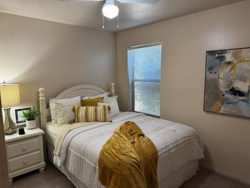 A bedroom with a white bed and a yellow blanket.