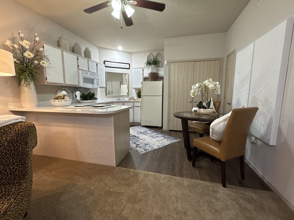 A kitchen with a leopard print chair and a dining table with a vase of flowers on it.