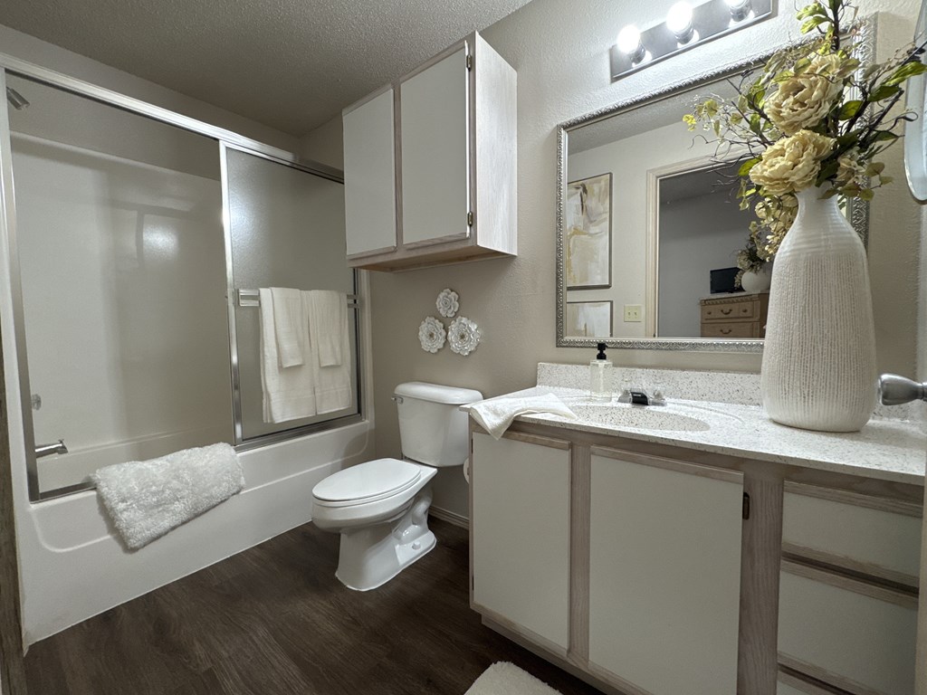 A white bathroom with a toilet, sink, and mirror.