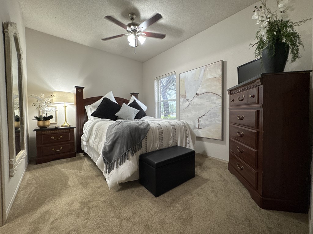 A bedroom with a bed, dresser, and a ceiling fan.