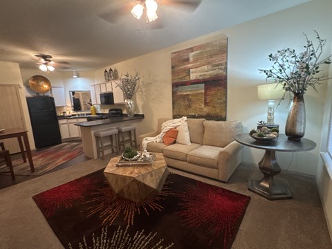 A living room with a white couch, a wooden coffee table, and a large abstract painting on the wall.