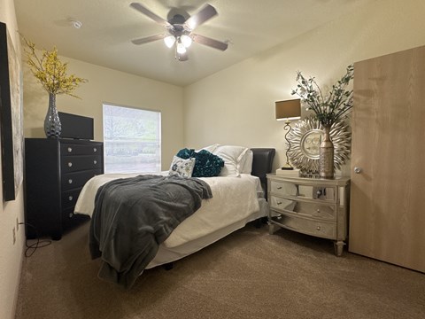 A bedroom with a bed, dresser, and ceiling fan.