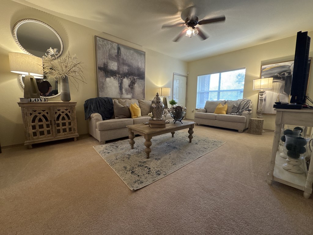 A living room with a white couch, a wooden coffee table, and a ceiling fan.