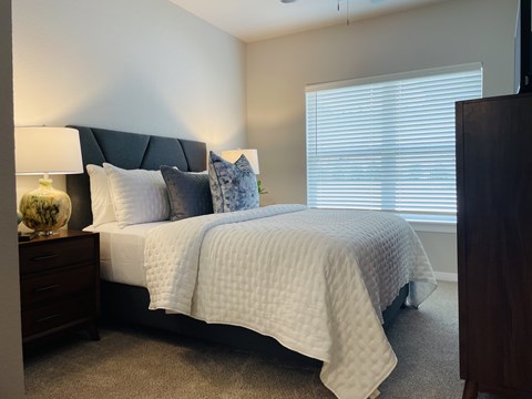 A bedroom with a bed, nightstand, and window.