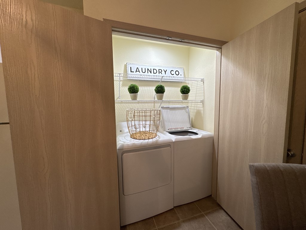 Laundry company sign on a wall above a washer and dryer.
