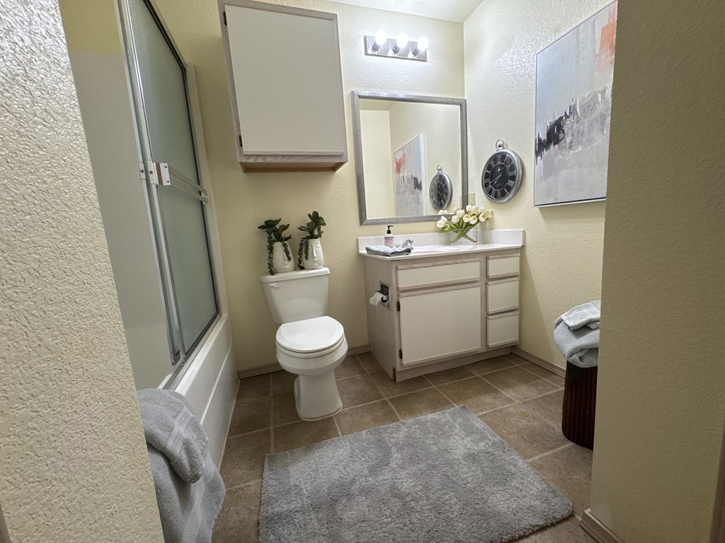 A bathroom with a toilet, sink, and mirror.