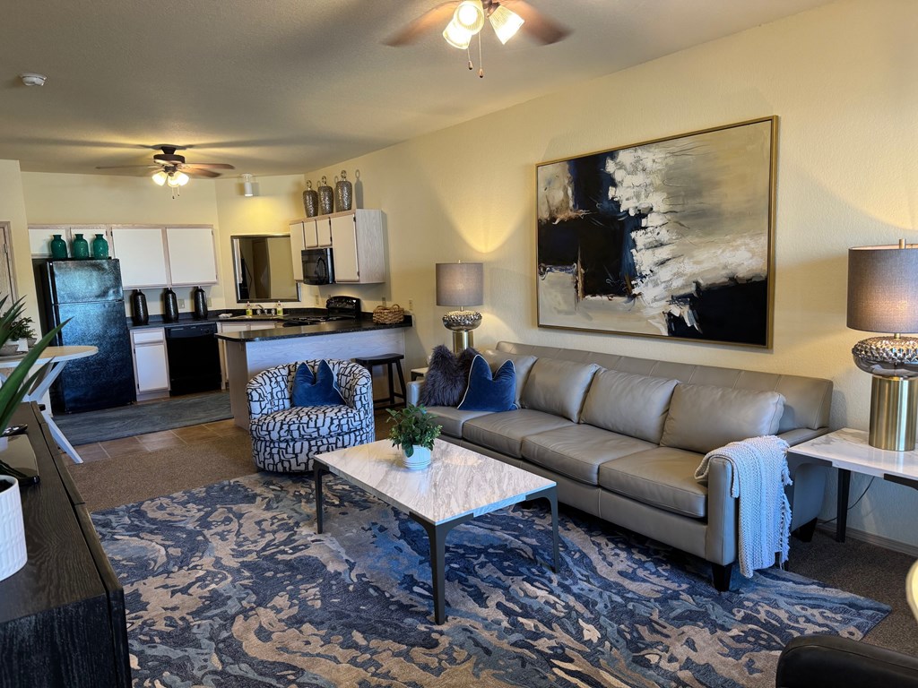 A living room with a grey couch and a painting on the wall.