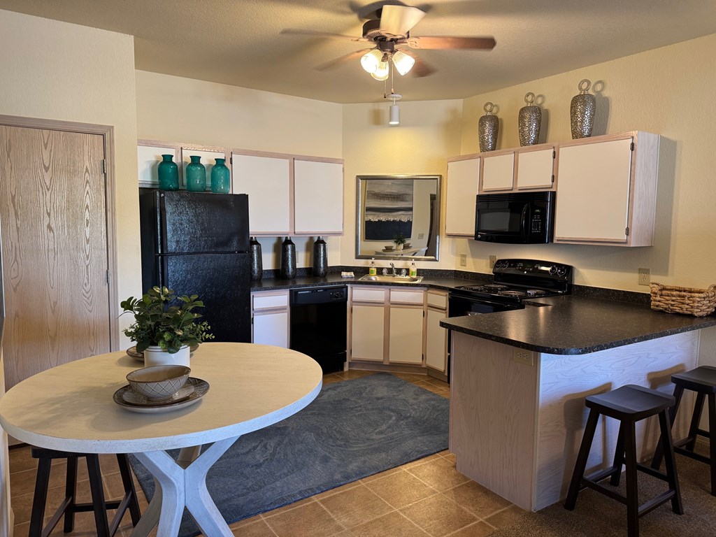 A kitchen with a black fridge and white cabinets.