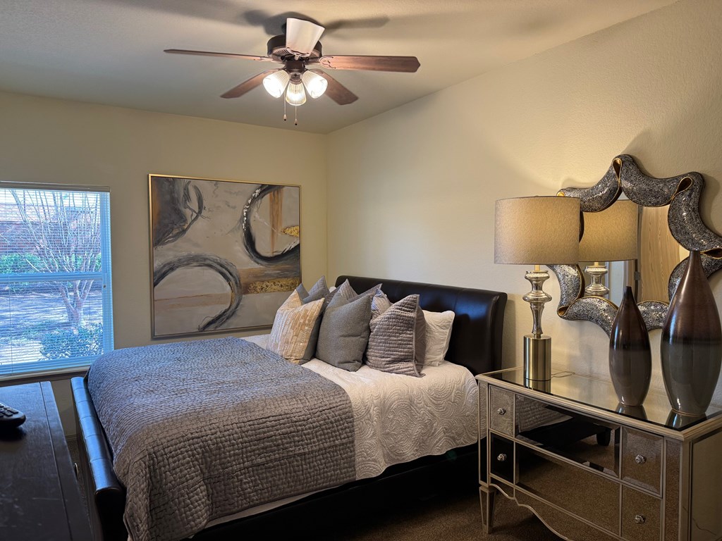 A bedroom with a bed, nightstand, and a painting on the wall.