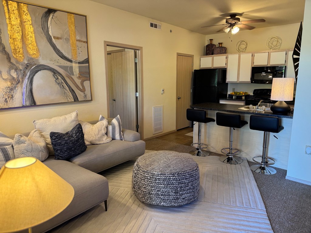 A living room with a grey couch, a yellow lamp, and a painting on the wall.