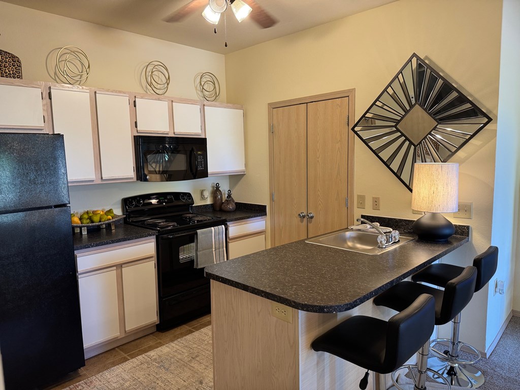 A kitchen with black appliances and white cabinets.