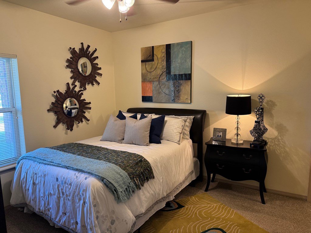 A bedroom with a bed, a nightstand, and a painting on the wall.