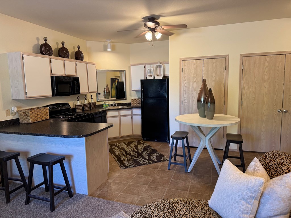 A kitchen with a black refrigerator and a black counter top.