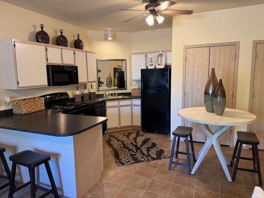 A kitchen with a black counter top and white cabinets.