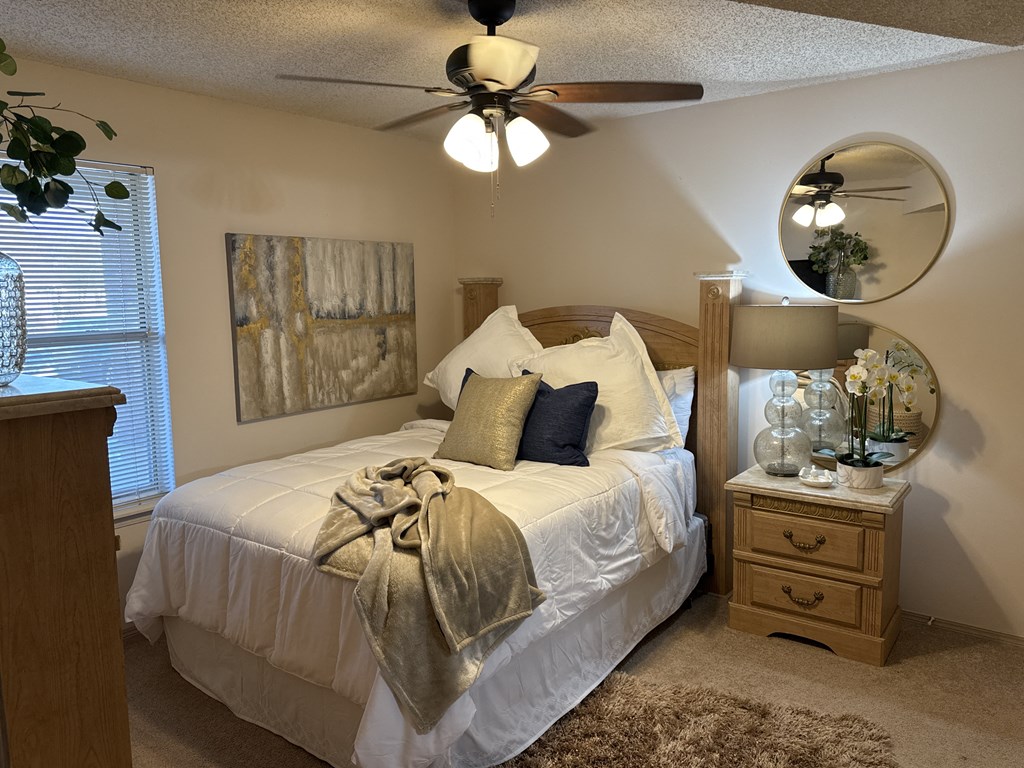 A bedroom with a bed, nightstand, and a ceiling fan.