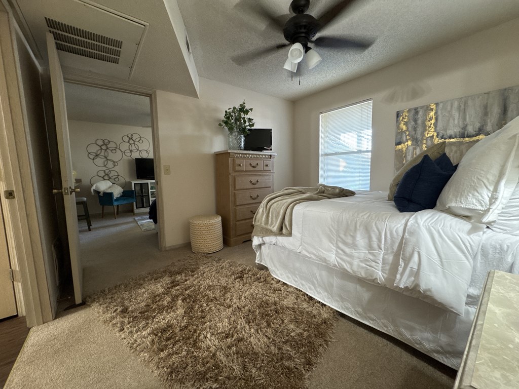 A bedroom with a bed, dresser, and ceiling fan.