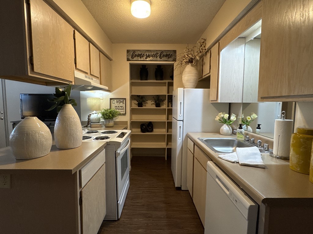 A kitchen with white appliances and wooden cabinets.