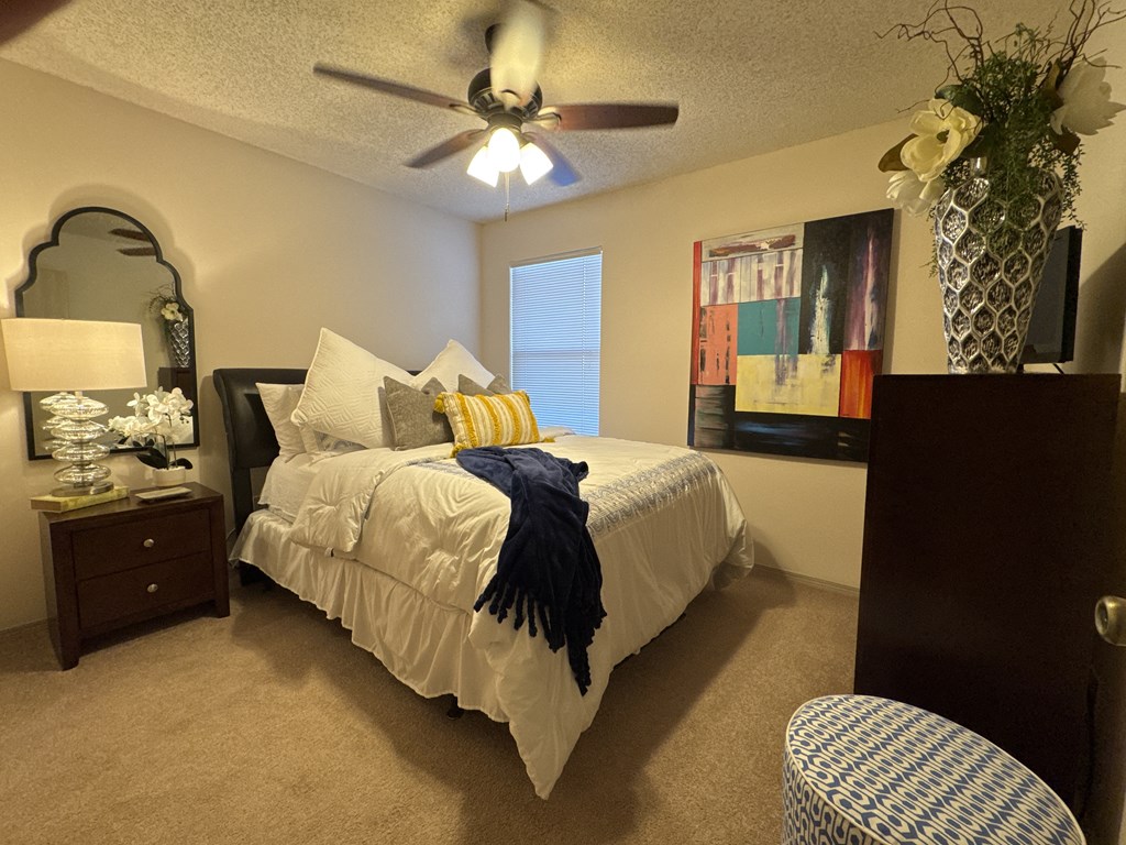 A bedroom with a bed, a ceiling fan, and a chair.