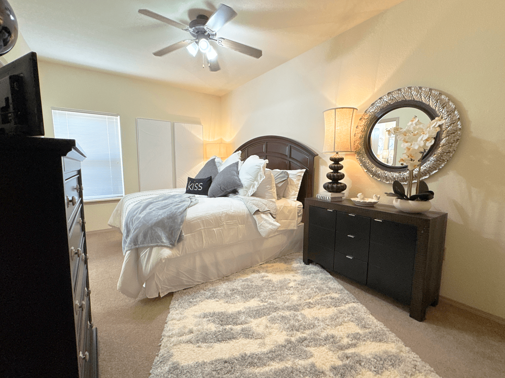 A bedroom with a bed, dresser, and mirror.
