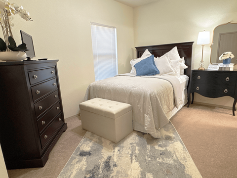 A bedroom with a bed, nightstand, and dresser.
