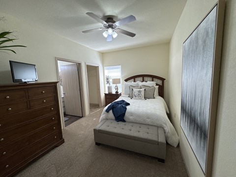 A bedroom with a bed, dresser, and ceiling fan.