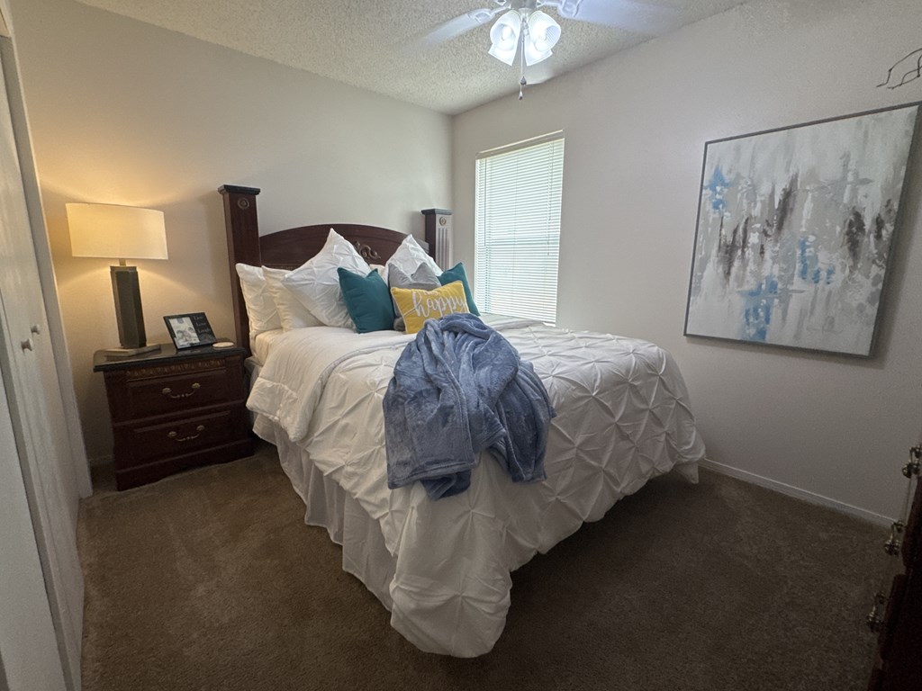 A bedroom with a large bed and a painting on the wall.