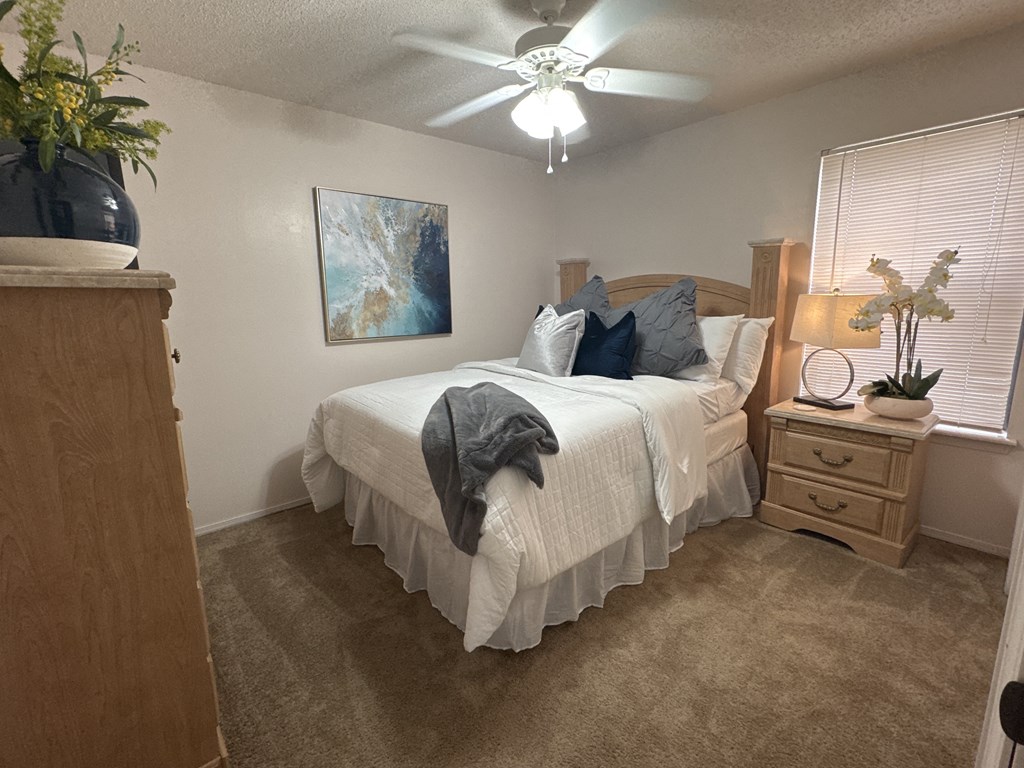 A bedroom with a bed, nightstand, and a painting on the wall.