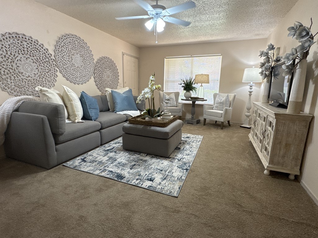 A living room with a grey couch, a coffee table, and a ceiling fan.