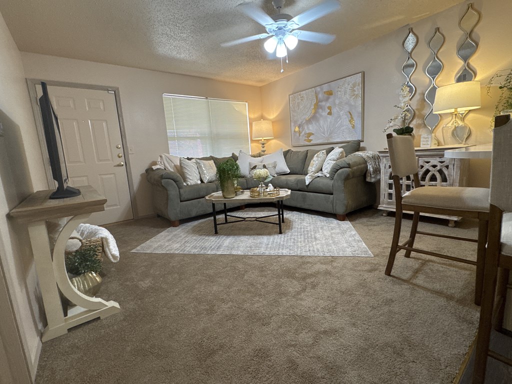 A living room with a grey couch and a white rocking chair.