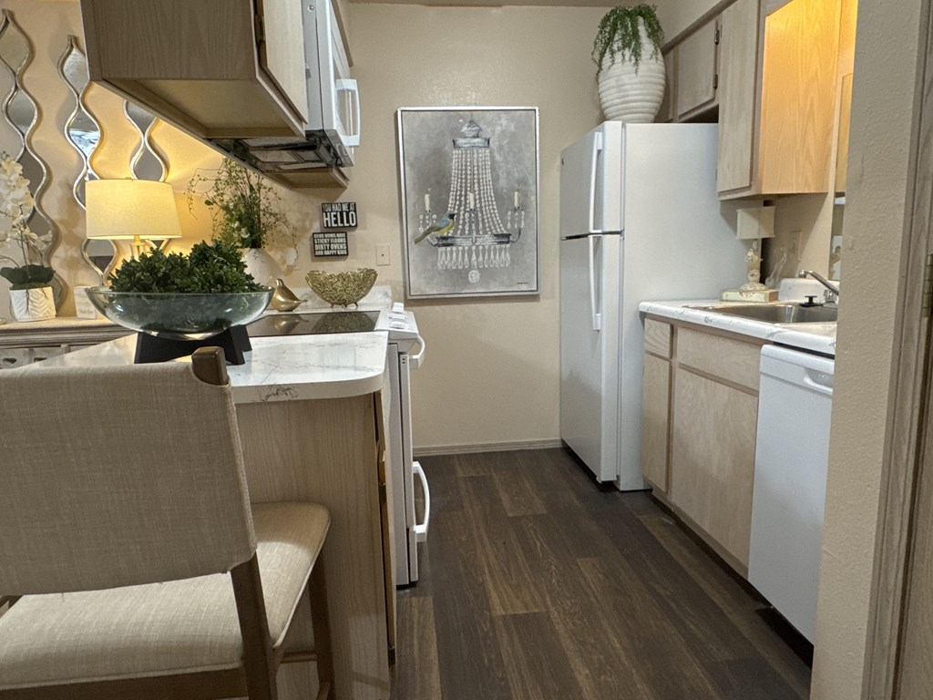 A kitchen with a white fridge, a table with a bowl on it and a chair.