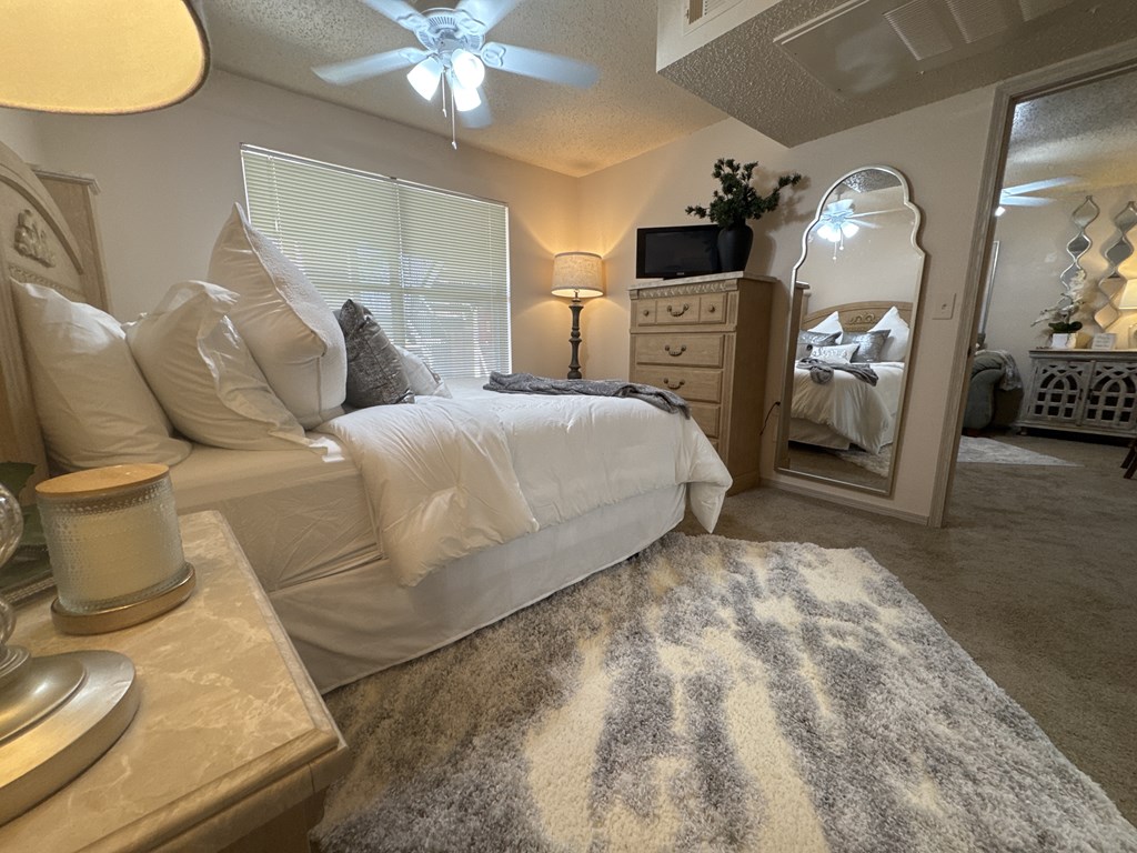 A bedroom with a large bed, a dresser, and a ceiling fan.
