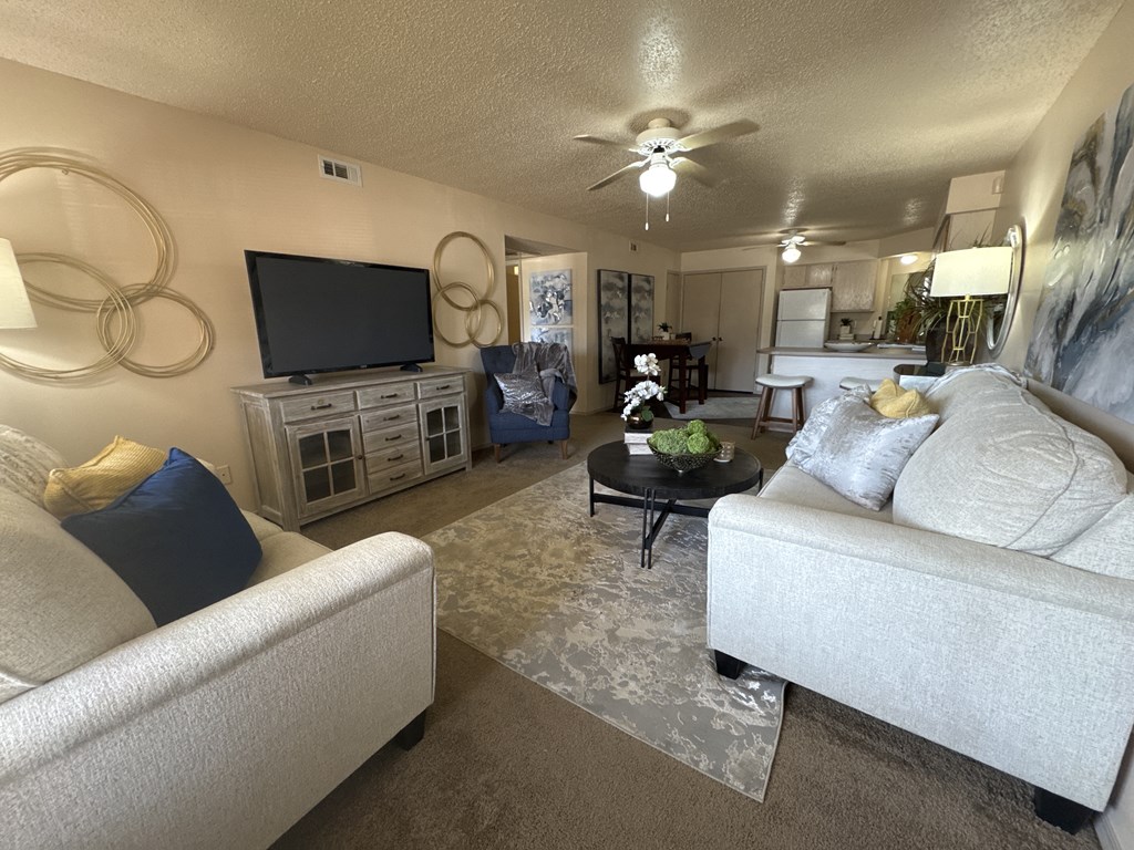 A living room with a white couch, a coffee table, and a flat screen TV.