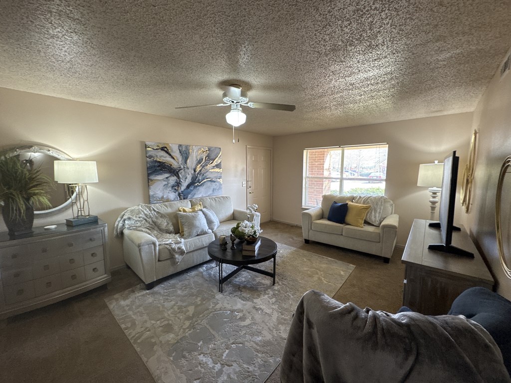 A living room with a white couch, a coffee table, and a ceiling fan.