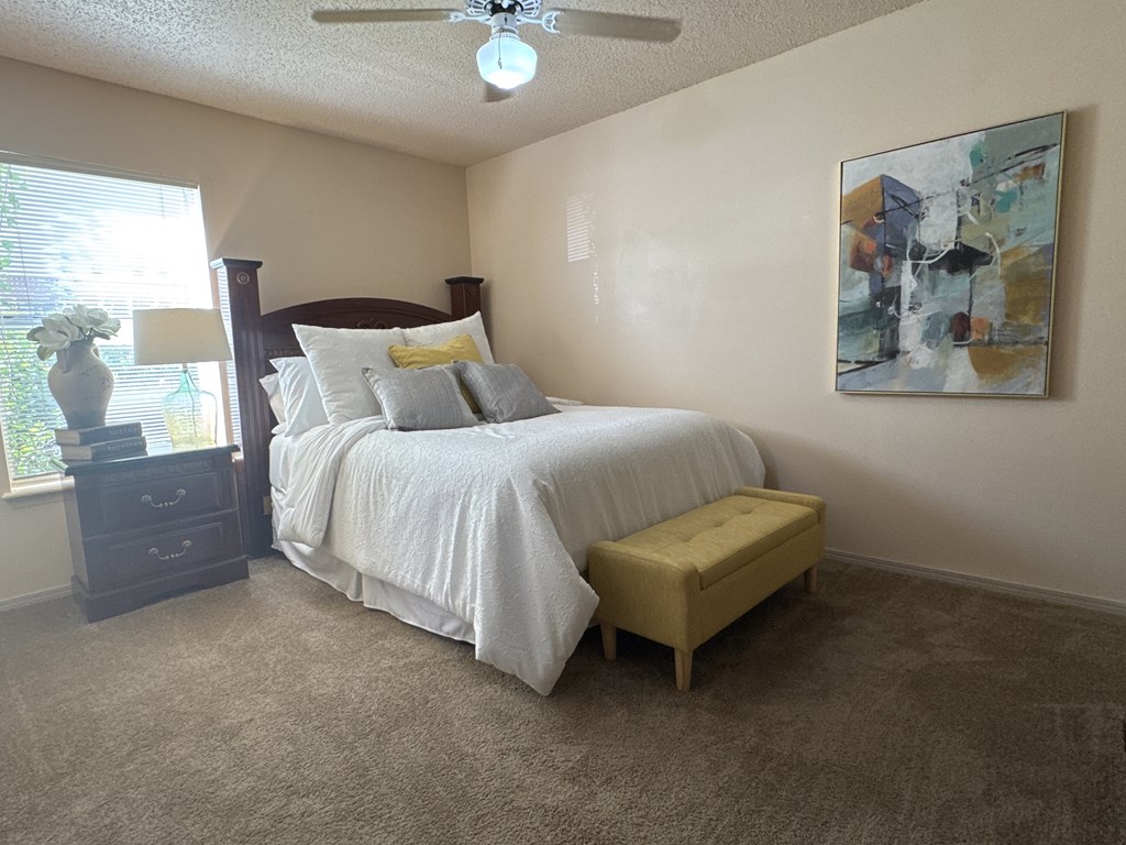 A bedroom with a bed, nightstand, and a painting on the wall.