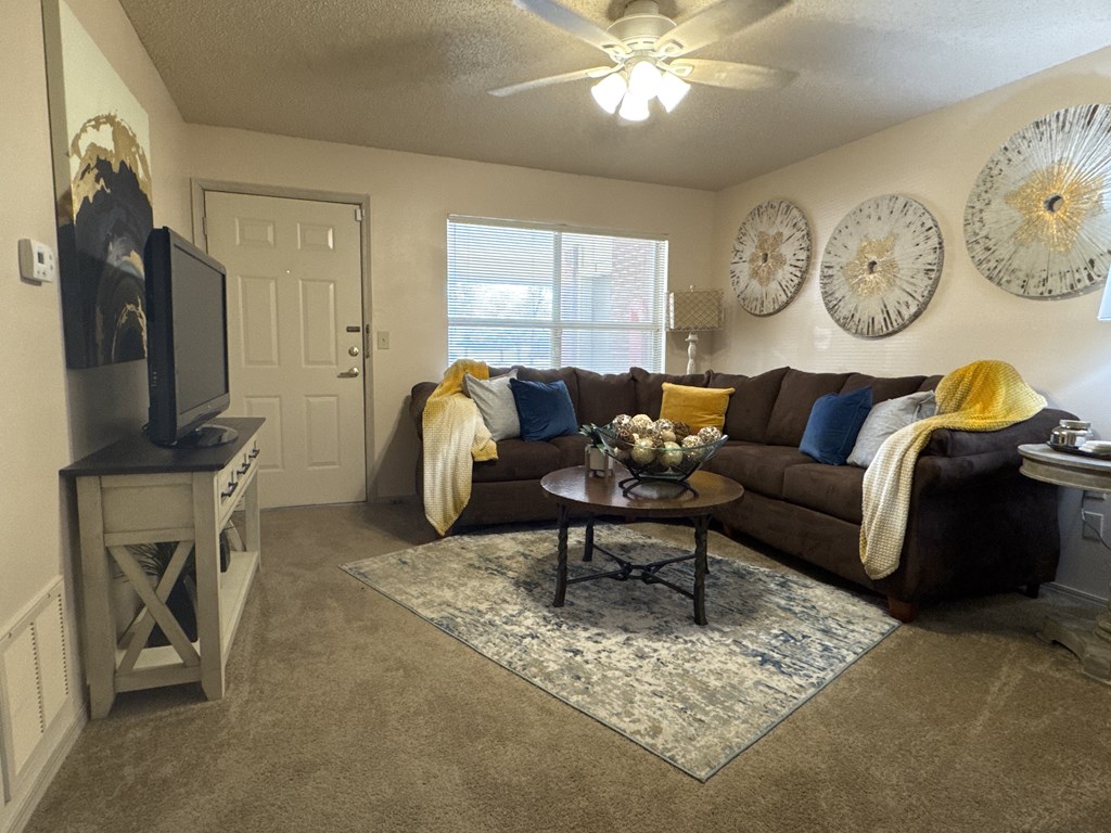 A living room with a brown couch and a ceiling fan.