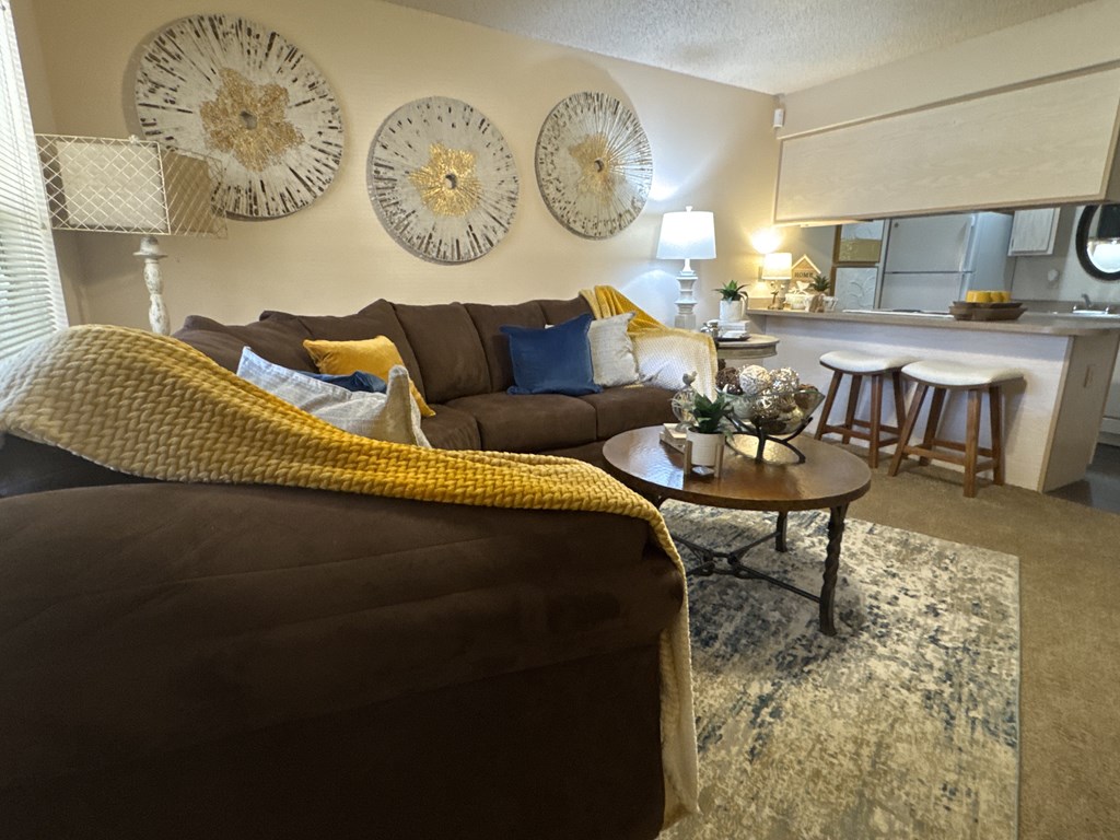 A living room with a brown couch and a yellow throw blanket.