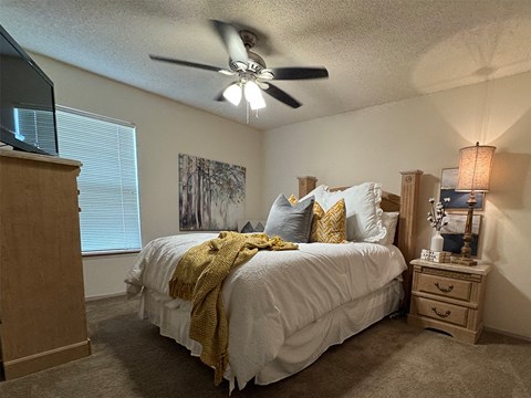 A bedroom with a bed, dresser, and ceiling fan.