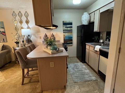 A kitchen with a black refrigerator and brown cabinets.