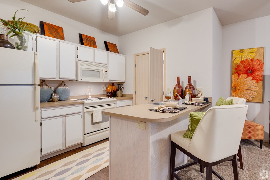 a kitchen with white appliances and a bar with a dining table