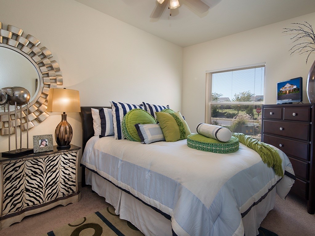 A bedroom with a bed, nightstand, and a mirror.
