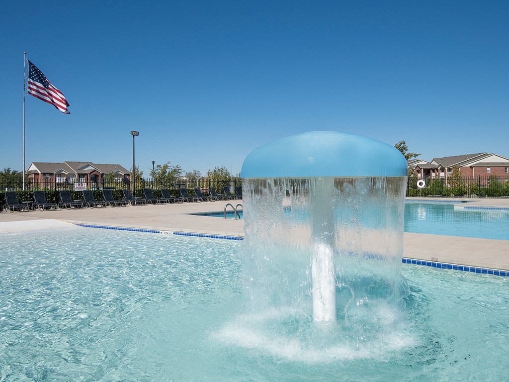 A blue water fountain in the middle of a pool.